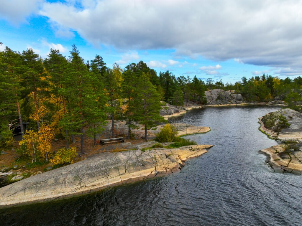 Rocky shore and pine trees beside a still, dark body of water